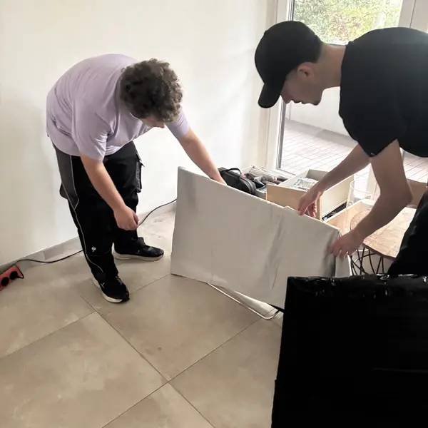 Zwei Mitarbeiter verpacken Möbel in einer hellen Wohnung